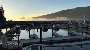 A marina with multiple docks and boats, surrounded by a hilly landscape.