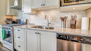 A modern kitchen with white cabinetry, a stainless steel dishwasher, and a microwave above the counter.