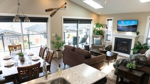 A modern kitchen with a built-in dishwasher, a dining area with a table set for four, and a cozy living room with a fireplace.