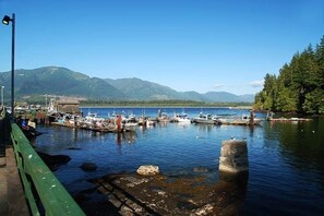 Ein Yachthafen mit vor Anker liegenden Booten, ein Grünanlage-Weg und Berge im Hintergrund.