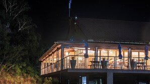 Um edifício de dois andares com varanda, janelas amplas e área para sentar ao ar livre.