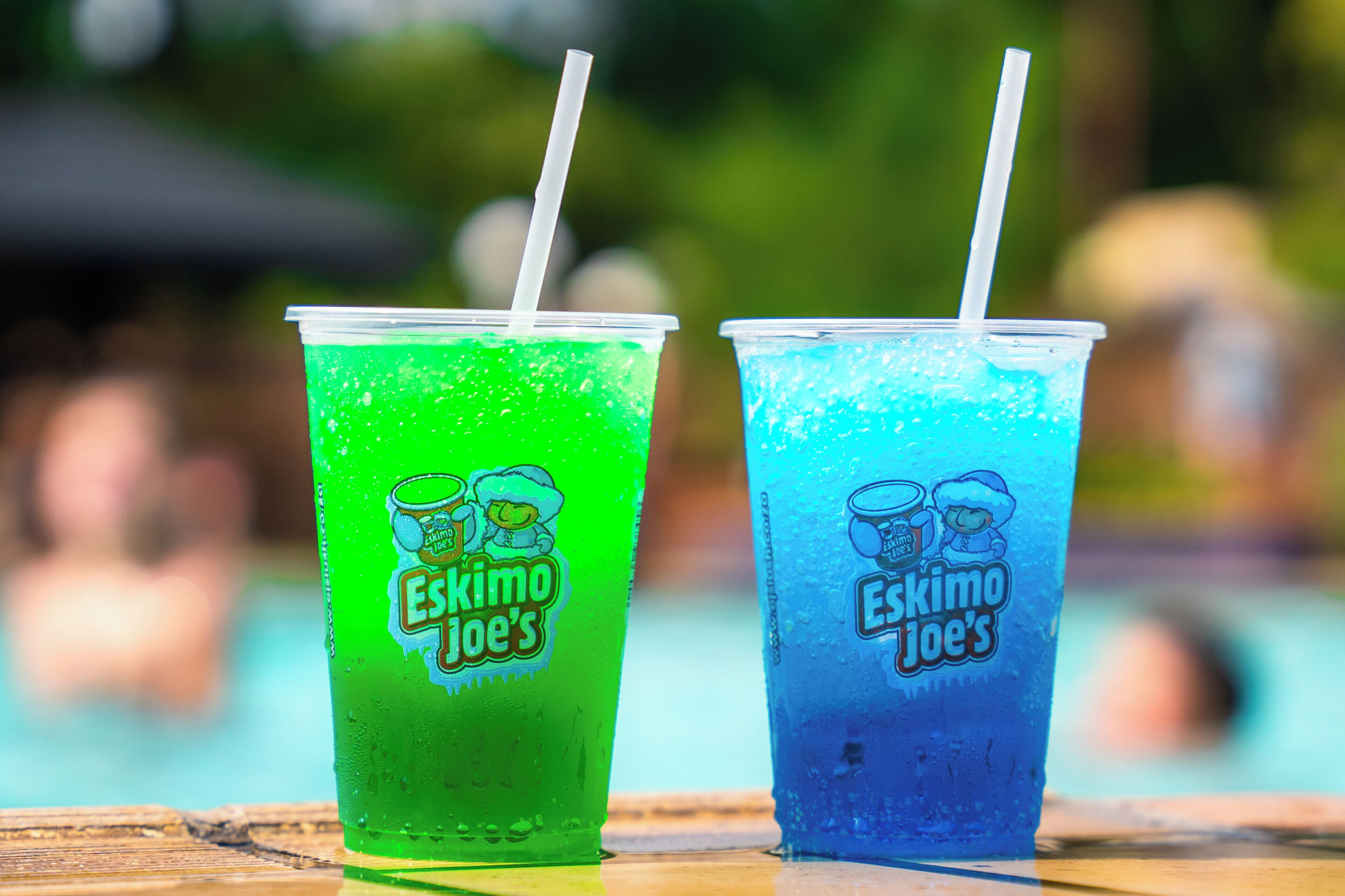 Dos vasos de plástico con pajitas, uno verde y otro azul, con la leyenda 'Eskimo Joe's'.