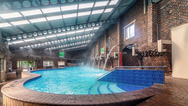 Uma piscina interna com parede de tijolos e piso revestido.