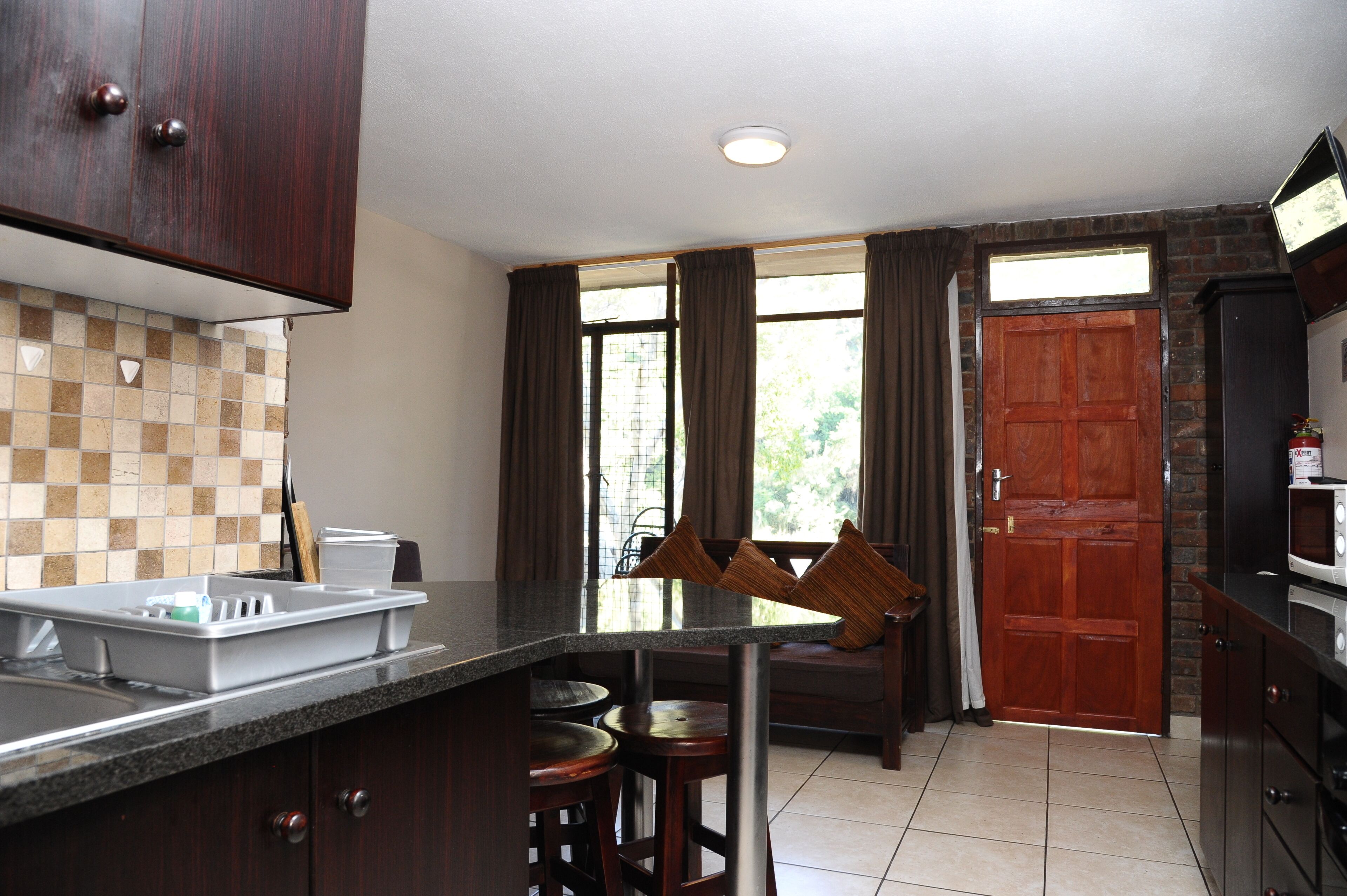 A kitchen with a granite countertop, wooden cabinets, a microwave, and a sink.
