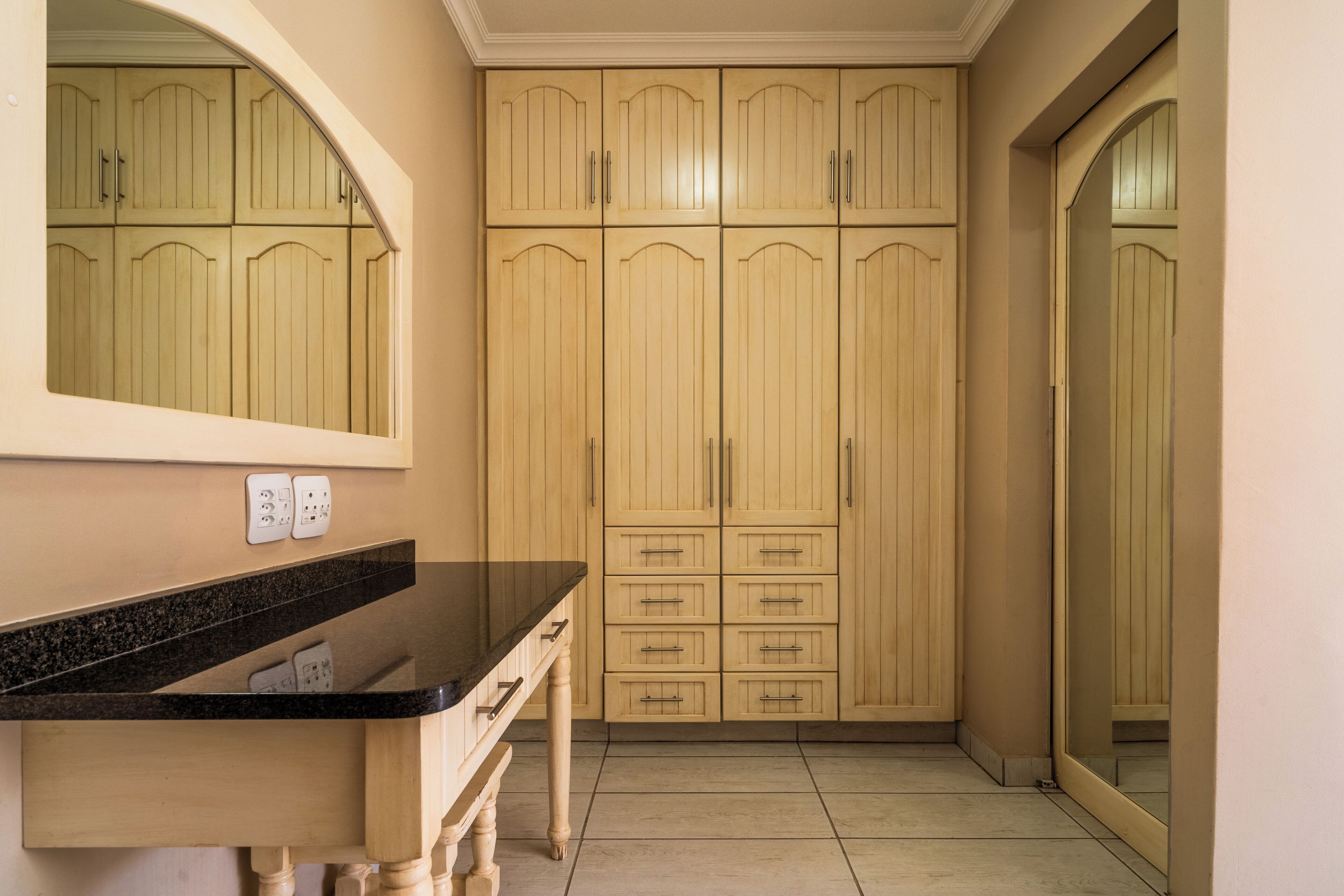 Una cocina con encimera negra, armarios de madera y un espejo sobre el lavabo.
