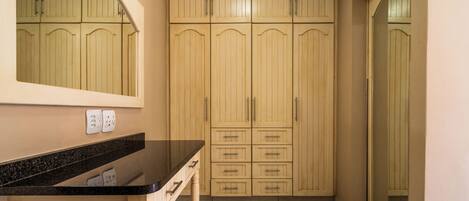 Una cocina con encimera negra, armarios de madera y un espejo sobre el lavabo.