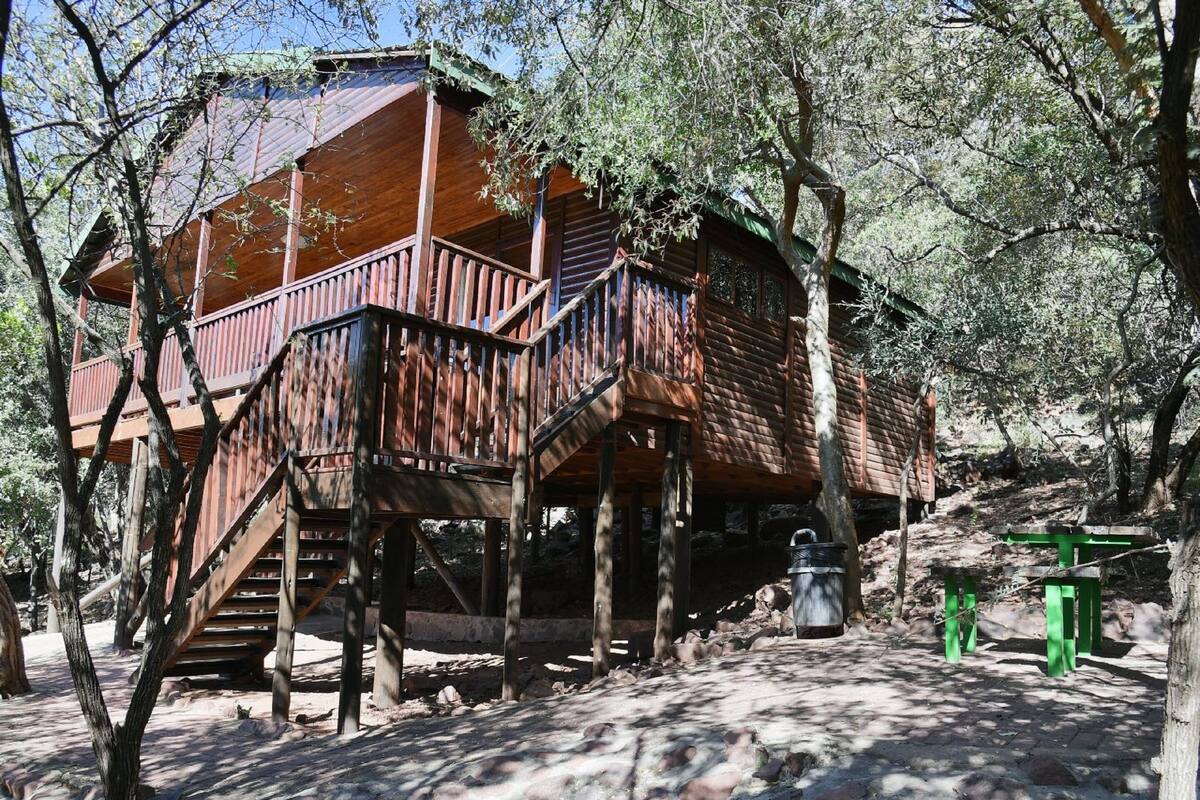 A wooden cabin with a wooden staircase leading to a deck.