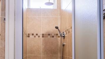 A shower area with a glass door, tiled walls, and a handheld showerhead.