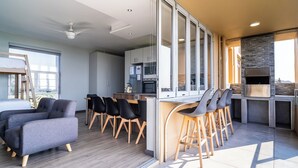 Eine moderne Küche mit Kamin aus Stein, einem Essbereich mit Barhocker und einer Sitzecke mit Sofas.