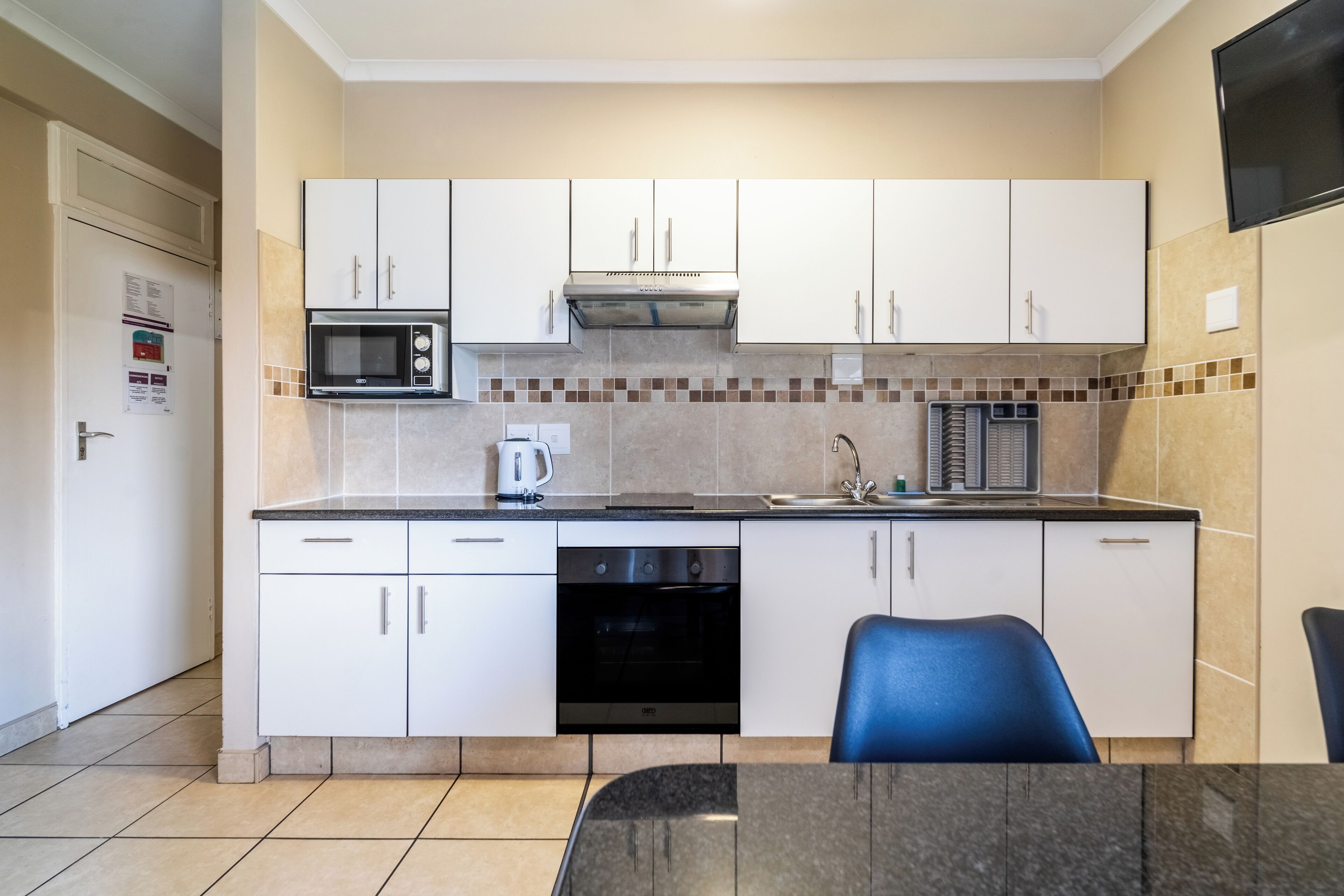 A compact kitchen with white cabinets, a microwave, a stove, and a dishwasher.