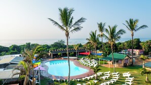 Ein Resort mit Swimmingpool, Liegestühlen und Palmen.