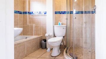 A bathroom with a toilet, a sink, a bathtub, and a glass-enclosed shower.
