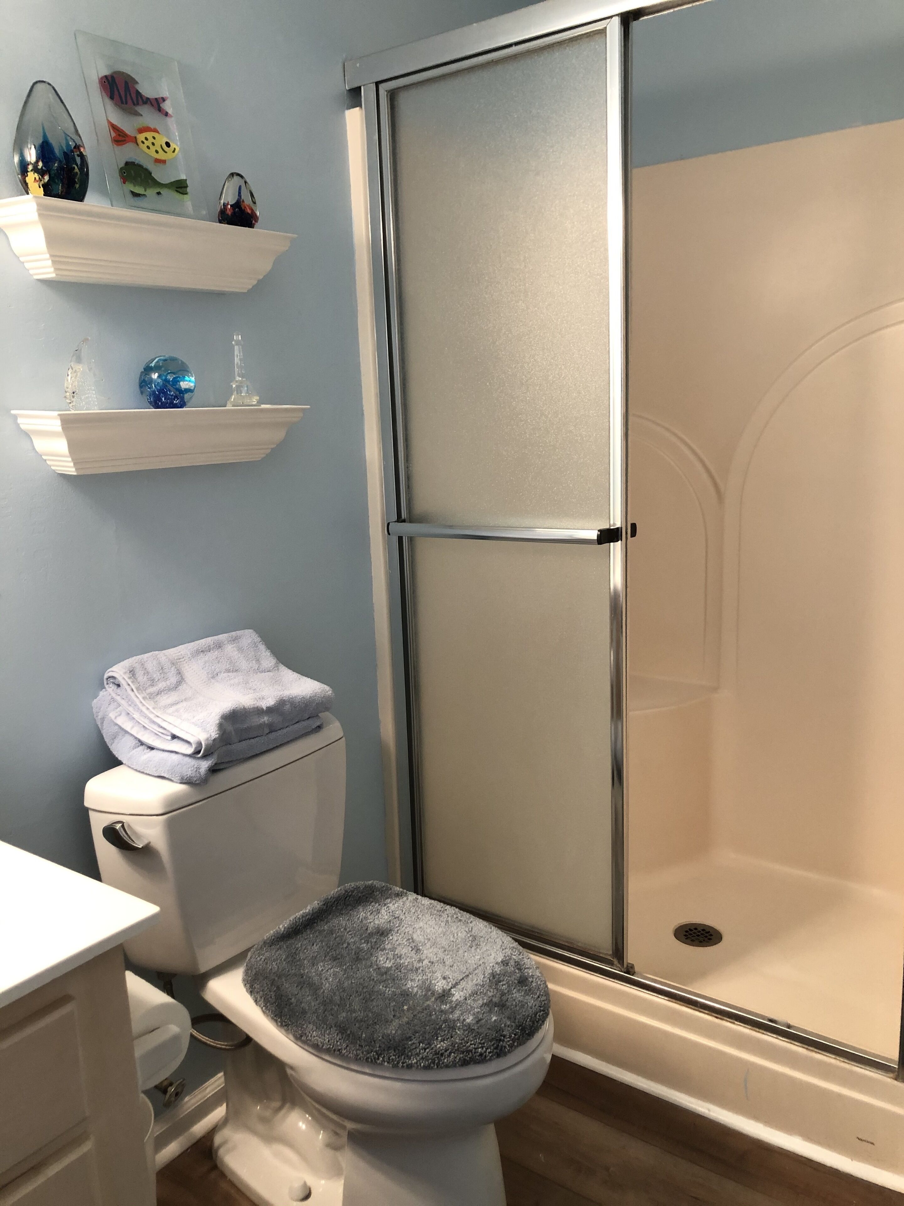 Casa de banho com sanita, cabine de duche e lavatório.