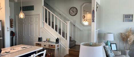 A living room with a dining area, a staircase, and a view of the upper floor.