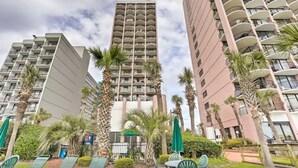 A high-rise hotel with multiple balconies, palm trees, and outdoor seating areas. - Lifes a beach on Myrtle Beach (Myrtle Beach)