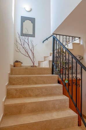 A staircase with beige steps, a black metal railing, and a wall-mounted light fixture. - Lacitrus Villa Hotel (Kas)