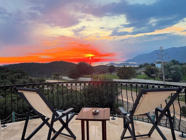 A balcony with two chairs and a small table, overlooking a scenic landscape with a sunset. - Lacitrus Villa Hotel (Kas)