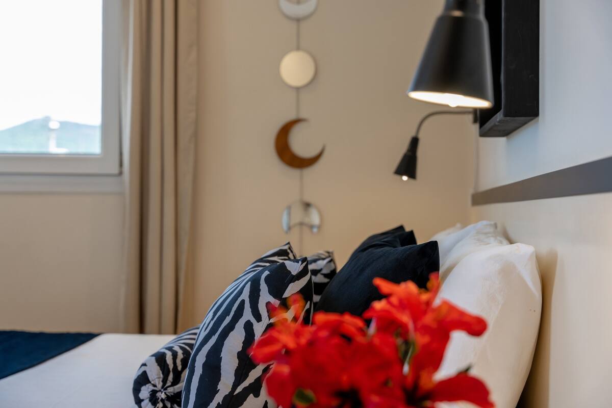 A bed with patterned pillows, a wall-mounted crescent moon decoration, and a lamp.