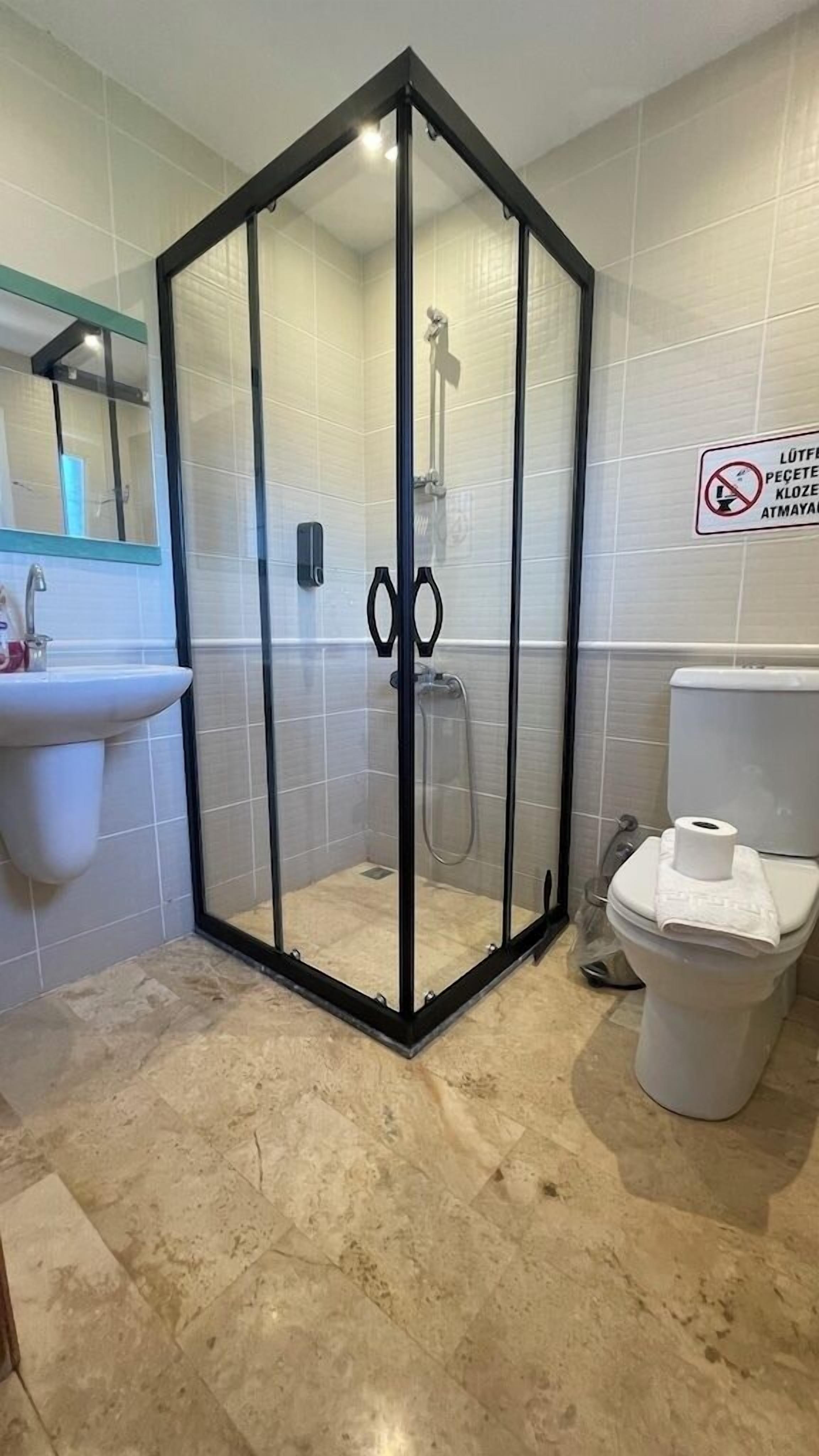 A bathroom with a glass-enclosed shower, a sink, and a toilet.