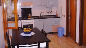 Een keuken met lichtblauwe kastjes, een zwart aanrecht, een spoelbak en een blauwe prullenbak.