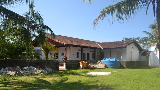 Una casa amb teulada de rajola, antena parabòlica i un dipòsit blau gran al pati.