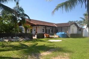 Une maison avec un toit en tuiles, une antenne parabolique et un grand réservoir d’eau bleu dans la cour.