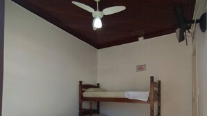 Una habitació amb una llitera, un llit individual i un ventilador de sostre.