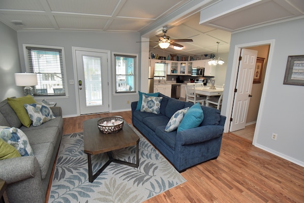 A living room with a sofa, coffee table, and a dining area with a table and chairs.
