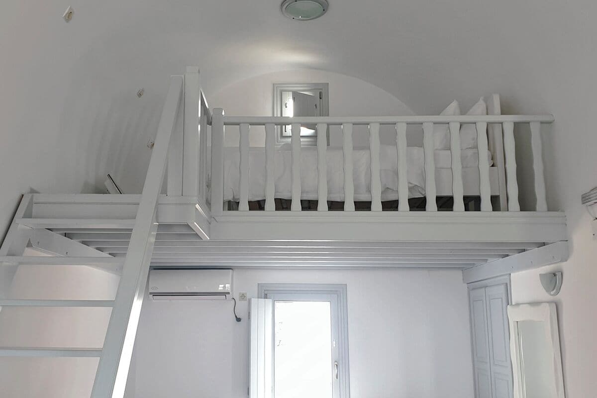 A white staircase with a railing leading to a loft bedroom.