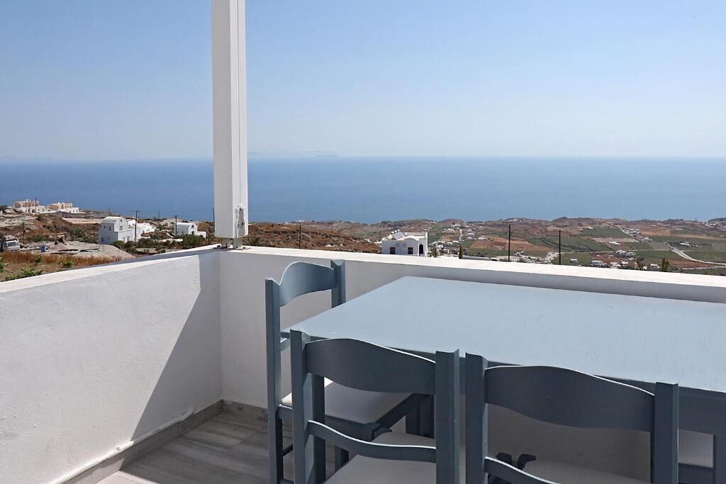 Un balcon avec une table et des chaises donnant sur un paysage côtier.