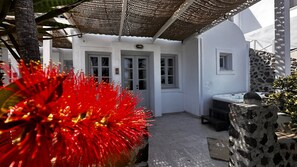 A white building with a covered patio area, stone walls, and a hot tub.