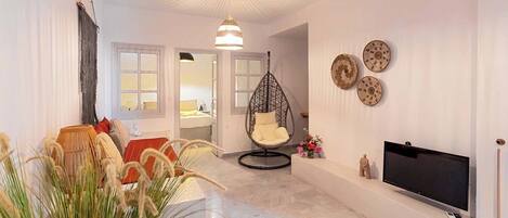 A modern living room with a hanging chair, a flat-screen TV, and decorative wall art.
