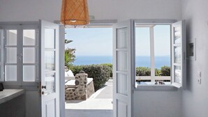 A room with a view of the sea, a stone bench, and a hanging light fixture. - Phaos Santorini Suites (Santorini)