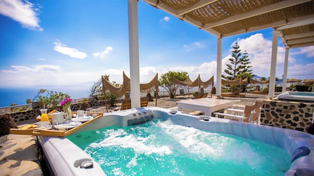 A hot tub with a tray of breakfast items, surrounded by outdoor seating and a view of the ocean. - Phaos Santorini Suites (Santorini)