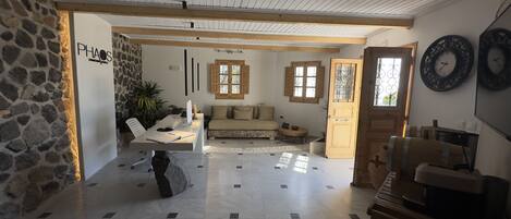 A spacious room with a stone wall, a wooden ceiling, and a large window.