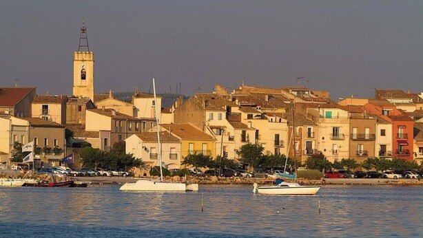 A coastal town with a prominent tower, waterfront buildings, and boats docked near the shore. - Apart 1 (Sleeps 4/6) Overlooking Etang De Thau Bouzigues, Languedoc-Roussillon (Bouzigues)