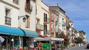 Une rue où se trouve un restaurant appelé « La table de Marie » et une enseigne pour l’agence immobilière « B.I Belles Immobilier ».