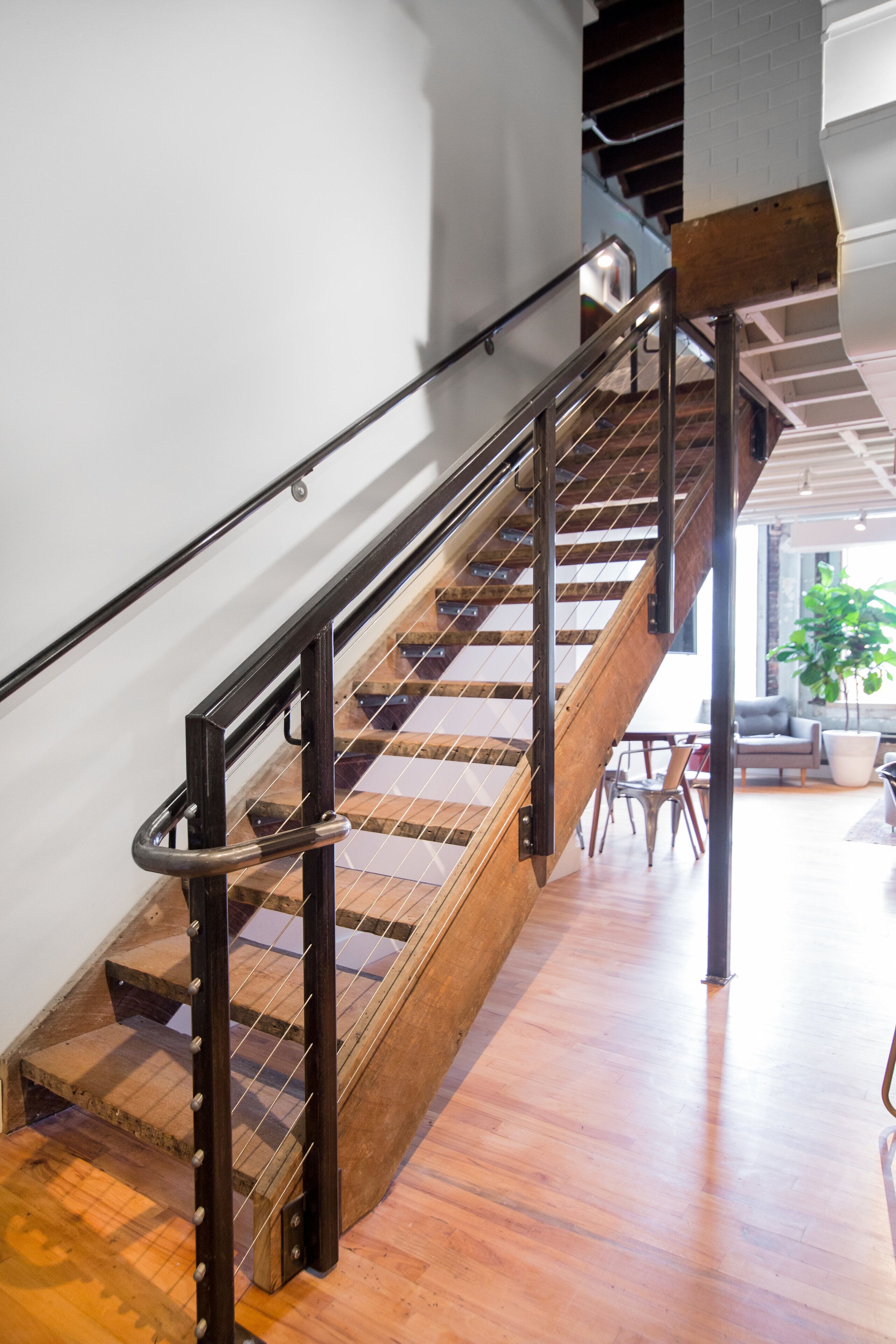 Un escalier en bois avec des rampes en métal, menant à un étage supérieur.