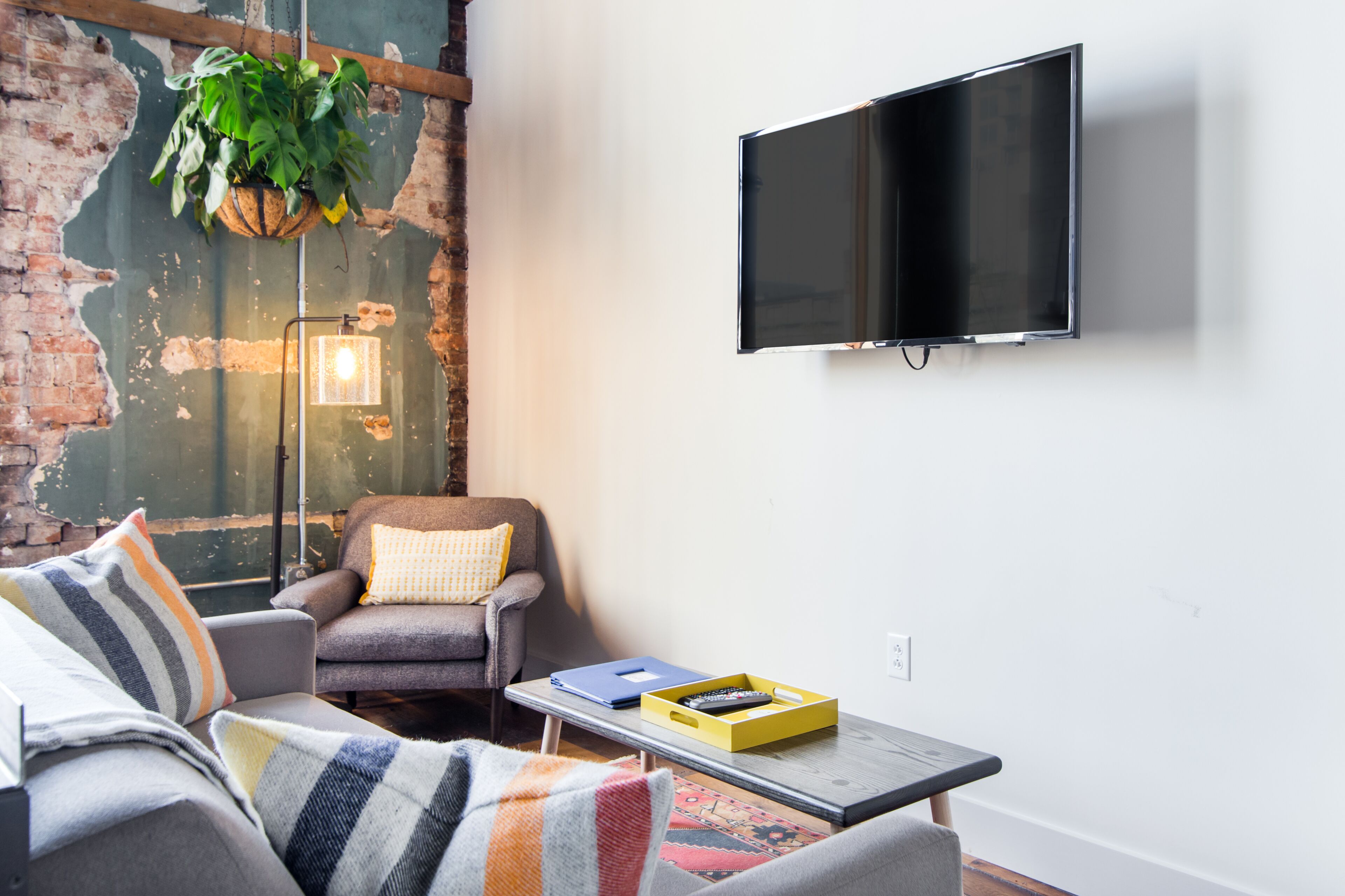 Una sala de estar con sofá, sillón y una mesa de centro con control remoto y un libro.