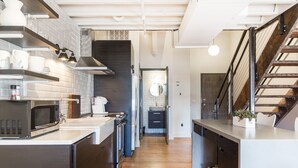 A modern kitchen with stainless steel appliances, a wooden floor, and a staircase leading to an upper level. - 506 Lofts - Anchor Rentals (Nashville)