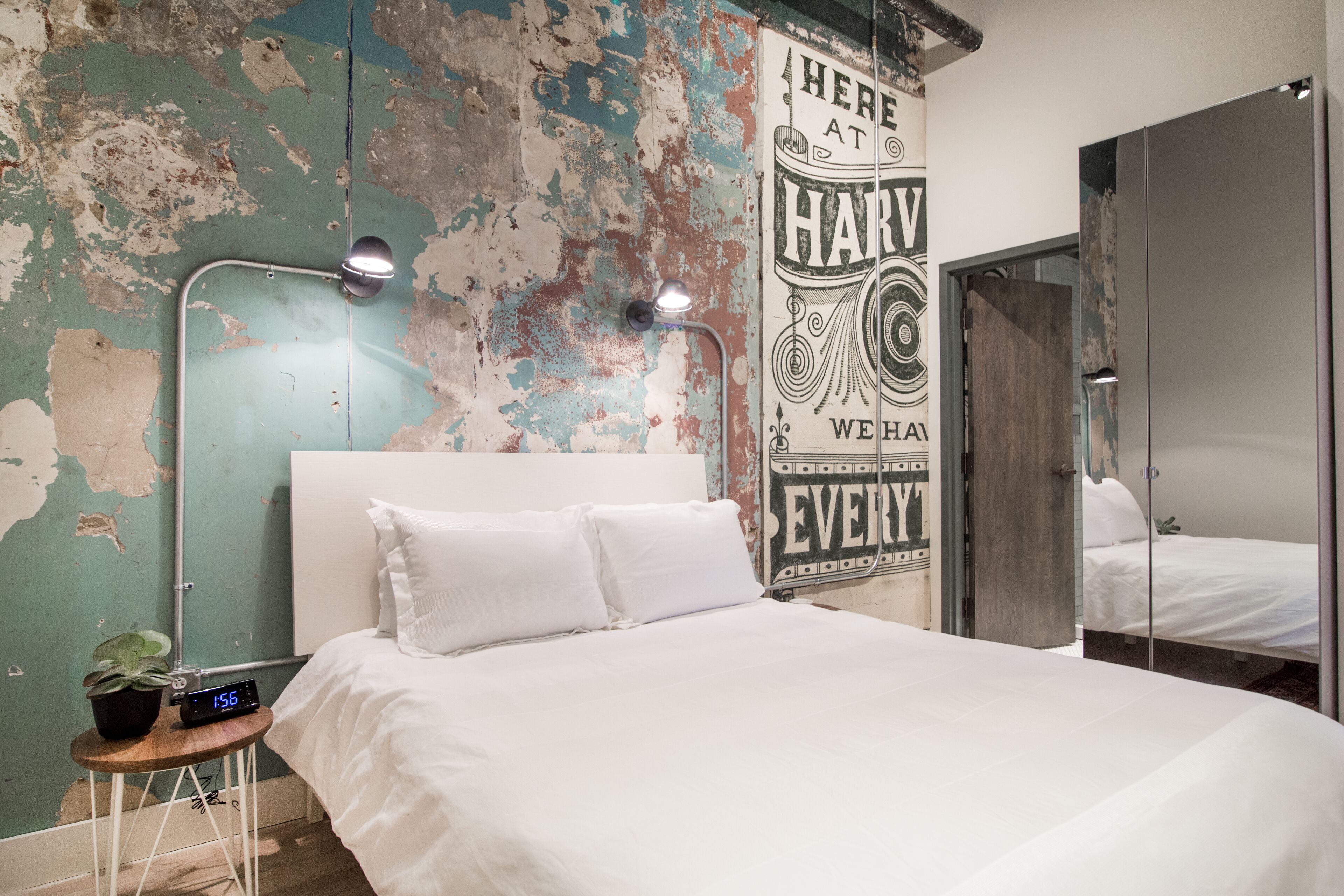 Une chambre à coucher avec un lit, une horloge murale, une plante en pot et une affiche.