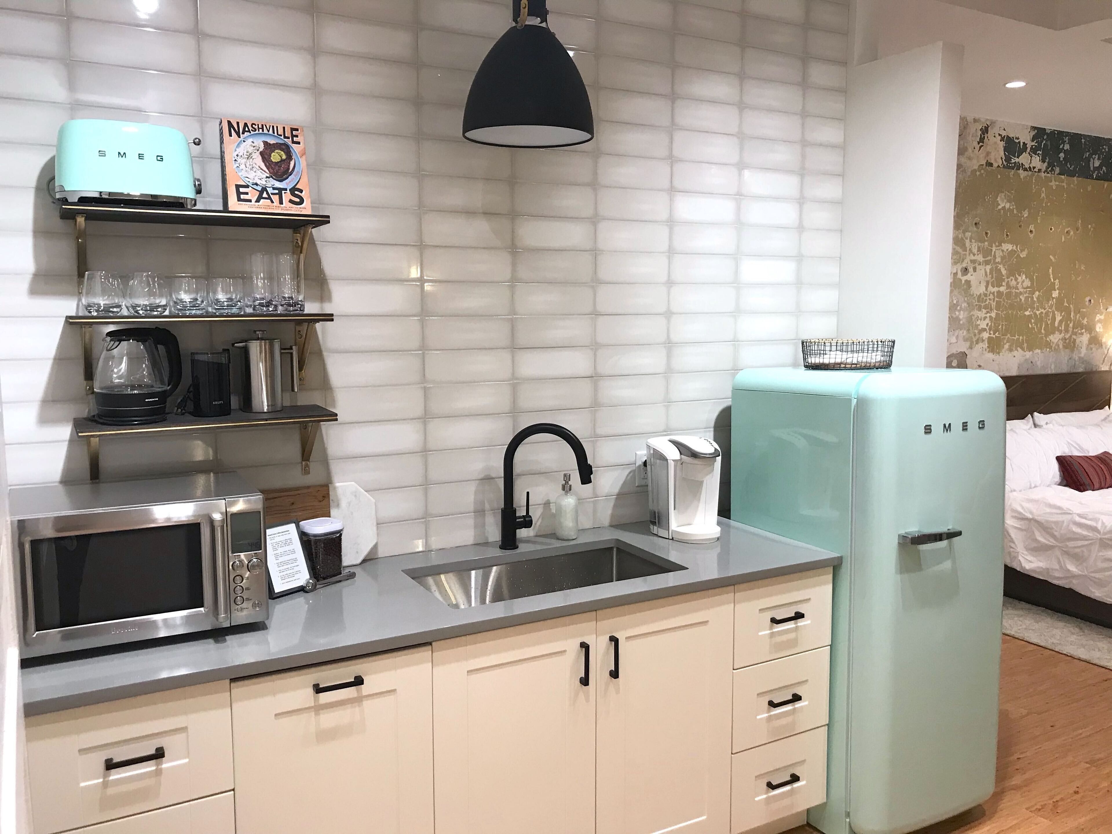 A modern kitchen with a microwave, coffee maker, and a light blue refrigerator.