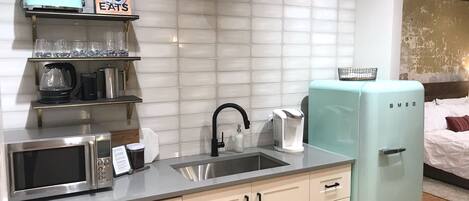 A modern kitchen with a microwave, coffee maker, and a light blue refrigerator.