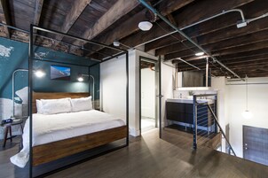 A modern bedroom with a wooden bed, a glass partition, and a view of the bathroom.