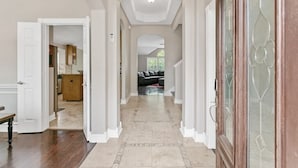 A hallway with a wooden bench, a door leading to a kitchen, and a glass door with a decorative pattern. - Beautiful Home, spacious office & Xbox Game Room. (Montgomery County)