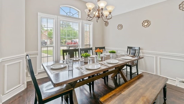 A dining room with a long wooden table set for six, white walls, and a chandelier. - Beautiful Home, spacious office & Xbox Game Room. (Montgomery County)