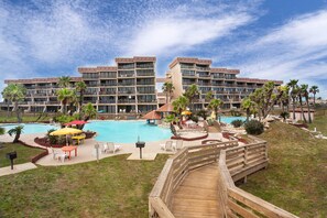 Un hotel con una piscina grande, mobiliario exterior y palmeras.