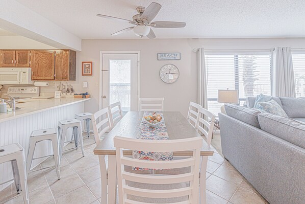 A spacious kitchen with wooden cabinets, a microwave, and a dining area with a table and chairs. - Do your dream beach vacation at Dune Dreams! (Navarre)