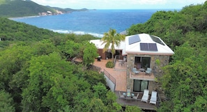 Uma casa com vista para o oceano, rodeada por vegetação.