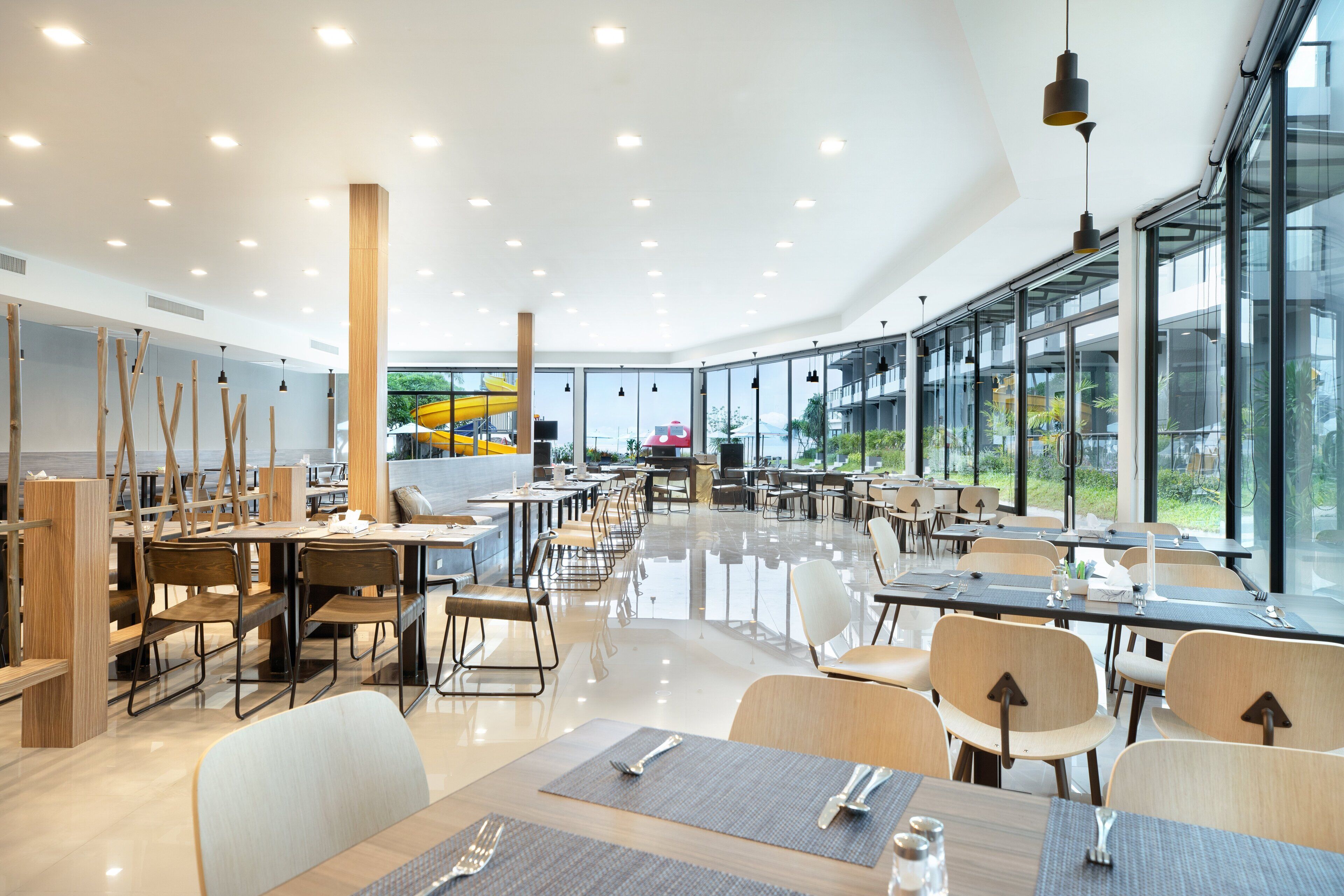 Un comedor espacioso con techos altos, ventanas grandes y mobiliario moderno.